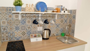 A kitchen with a tiled backsplash, a shelf with dishes, a kettle, and a box of tea. - Apricot House. In the heart of the old town. (Bari)
