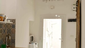 A kitchen with a washing machine, a microwave, and hanging light fixtures. - Apricot House. In the heart of the old town. (Bari)