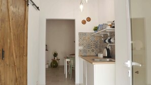 A kitchen with a wooden door, a dining area with a table and chairs, and a tiled backsplash. - Apricot House. In the heart of the old town. (Bari)