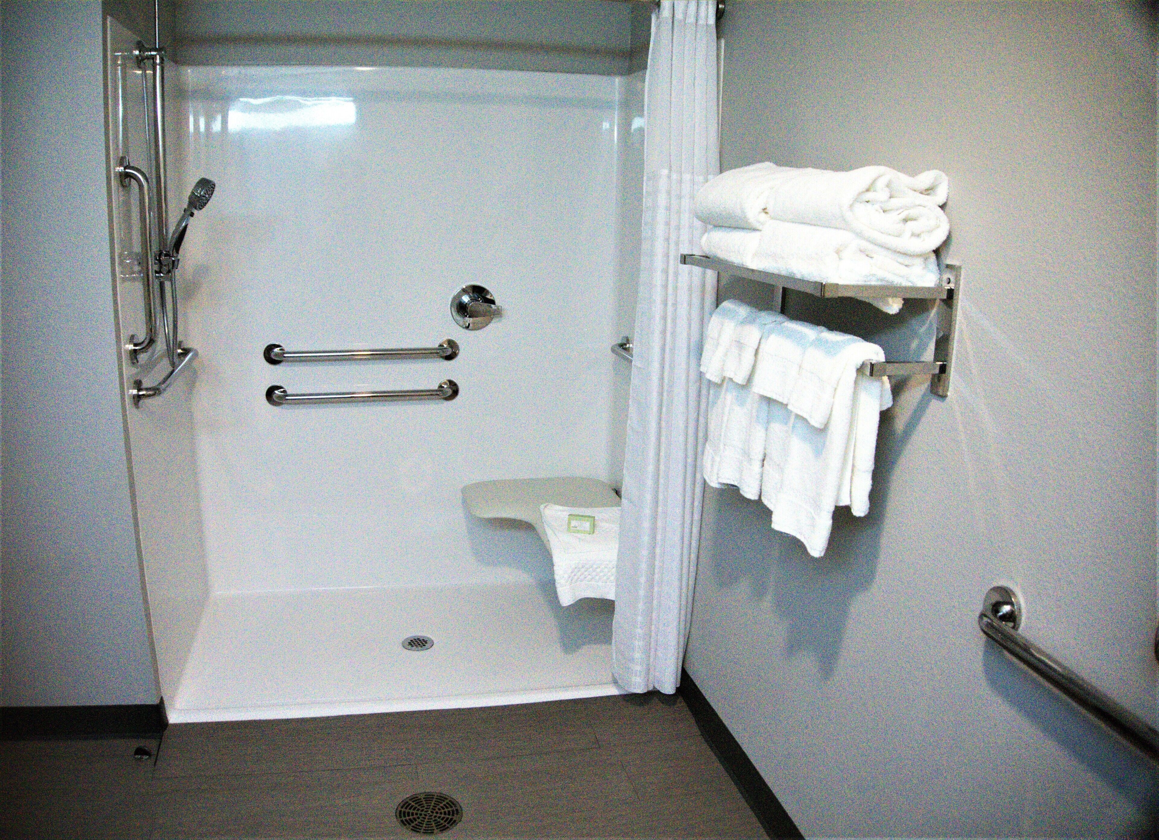 A shower with a glass door, a towel rack with towels, and a grab bar.