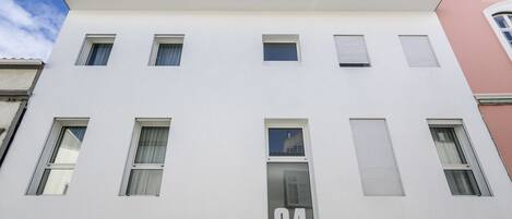 Un edificio moderno con fachada plana, múltiples ventanas y el número '64' destacado en la parte frontal.