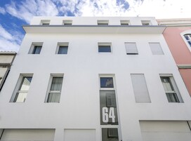 A modern building with a flat facade, multiple windows, and a prominent number '64' on the front.