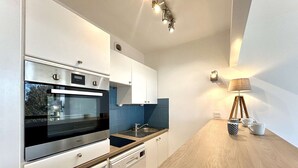 Una cocina moderna con electrodomésticos de acero inoxidable, armarios blancos y encimera de madera.