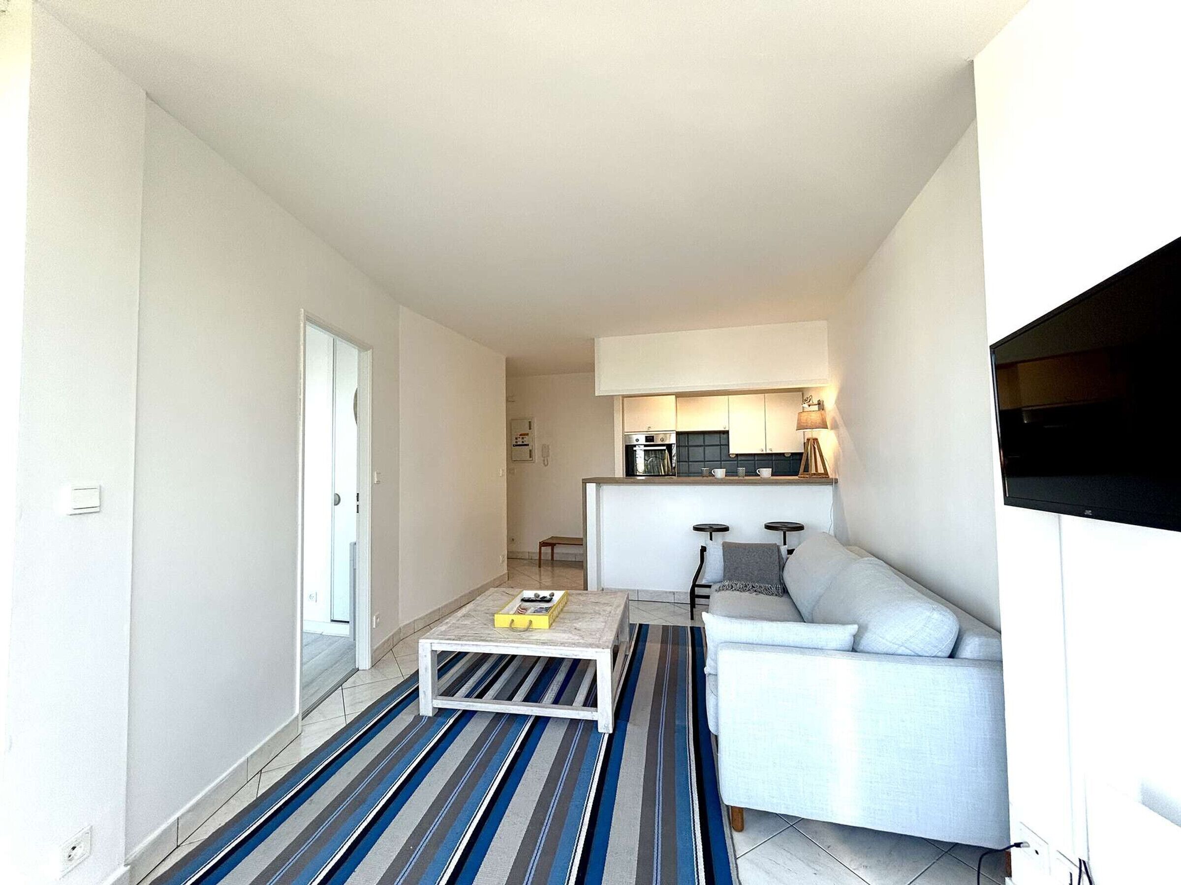 A modern apartment with a living area, a kitchen, and a dining space.