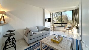 Una sala de estar moderna con un sofá, una mesa de centro y un ventanal con cortinas.