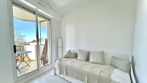 Un dormitorio con cama, una mesita de noche y vistas a un área exterior con mesa y sillas a través de un ventanal corredero.