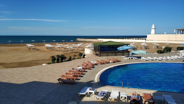A resort with a swimming pool, beach area, and a lighthouse in the background. - Khazar Golden Beach (Baku)