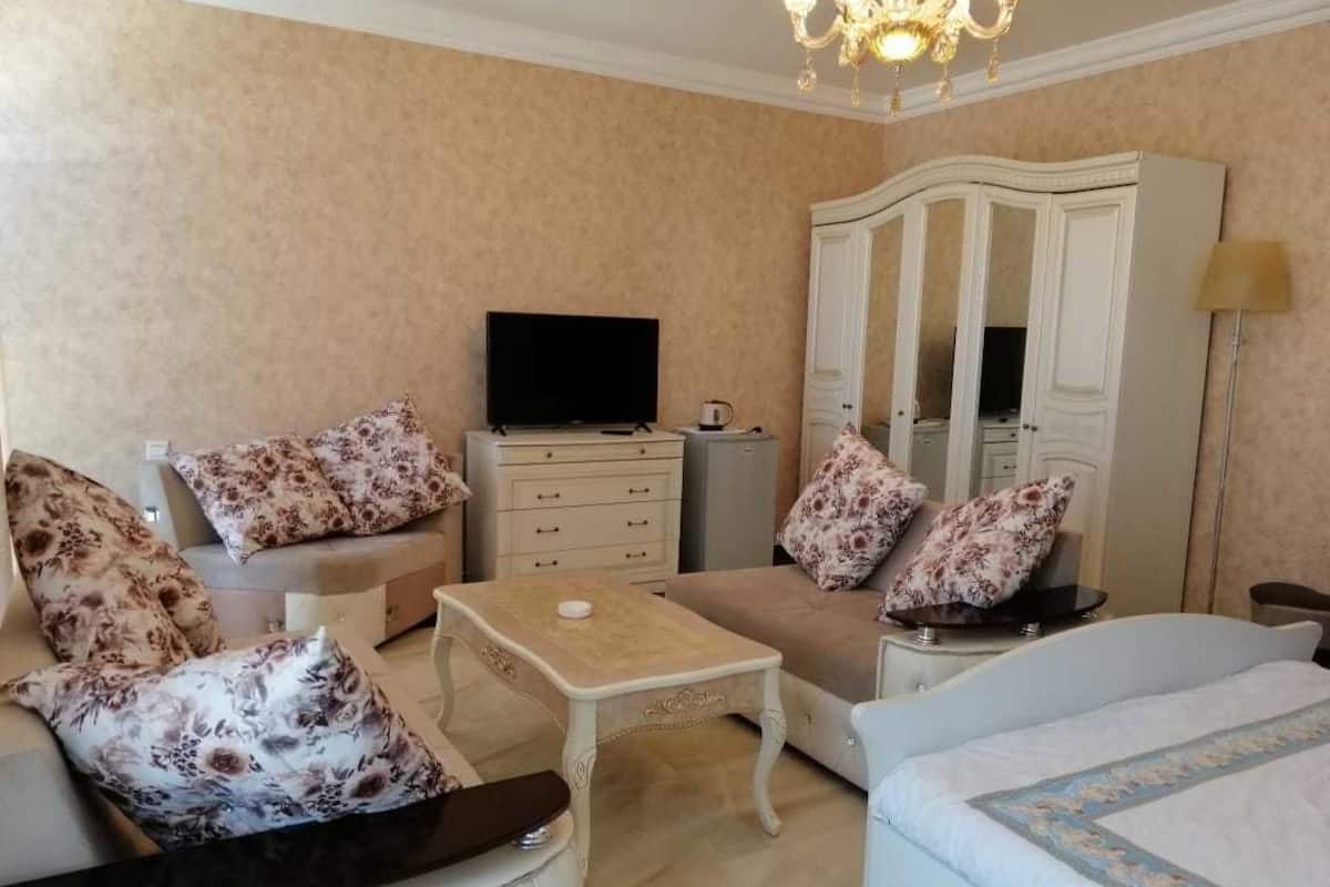 A well-furnished living room with a sofa, armchair, coffee table, and a television.