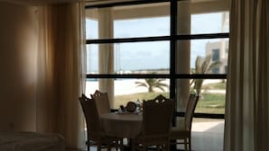 A dining area with a table and chairs, large windows with curtains, and a view of the outdoors. - Khazar Golden Beach (Baku)