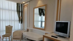 A hotel room with a white desk, two chairs, a television, and a mirror. - Khazar Golden Beach (Baku)