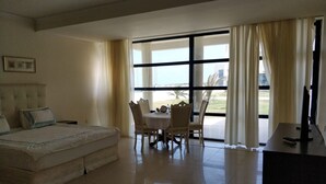 A hotel room with a bed, a dining table with chairs, a TV, and large windows with curtains. - Khazar Golden Beach (Baku)