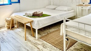 Une chambre à coucher blanche avec un lit, une table de chevet et un luminaire suspendu.