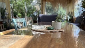 Une table en bois surmontée d’une plaque de verre, une petite plante en pot et un cendrier en verre.