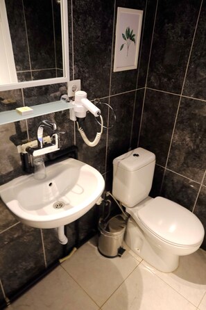 A bathroom with a white sink, toilet, and a hairdryer on the wall. - L'onda Oda Bodrum (Bodrum)