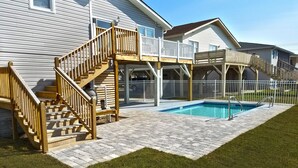 A residential property with a wooden deck, a swimming pool, and a covered patio area.