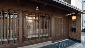 Il s’agit d’un bâtiment japonais traditionnel doté de portes coulissantes, d’une façade en bois et d’un petit espace d’entrée agrémenté d’un paillasson.