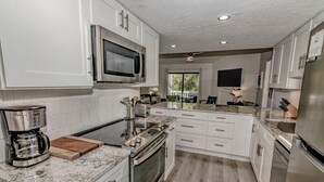 Una cocina moderna con armarios blancos, electrodomésticos de acero inoxidable y piso de madera.