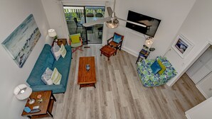 Amplia sala de estar con un sofá azul, una mesa de centro de madera y un sillón de peluche colorido.