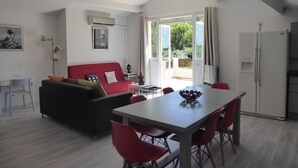 Un soggiorno moderno con un divano rosso, un tavolo da pranzo con sedie rosse e una ventola a soffitto.