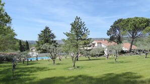 Zona verdeggiante all'aperto con alberi e un edificio sullo sfondo.