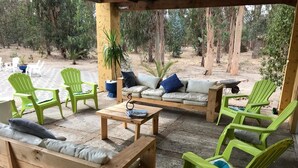 Un patio exterior con mobiliario de madera, incluyendo un sofá, sillas y una mesa.