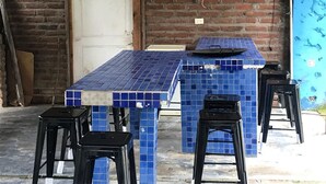 Un área de estar al aire libre con encanto, con una barra cubierta de azulejos y taburetes negros.