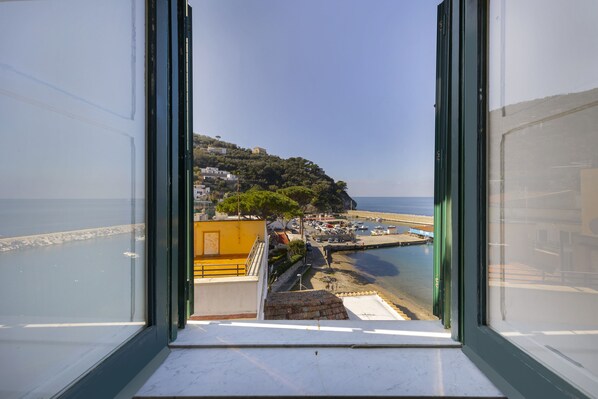 A view from a window overlooking a coastal area with buildings, a marina, and a beach.
