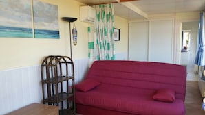A room with a red sofa, a wooden side table, a floor lamp, and a patterned rug. - Spacious and cozy studio with breathtaking views (Saint-Mandrier-sur-Mer)