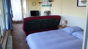 A hotel room with two beds, a television, a life preserver decoration, and a window with curtains. - Spacious and cozy studio with breathtaking views (Saint-Mandrier-sur-Mer)