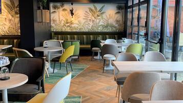 A restaurant interior with a tropical mural, green booths, and wooden flooring.