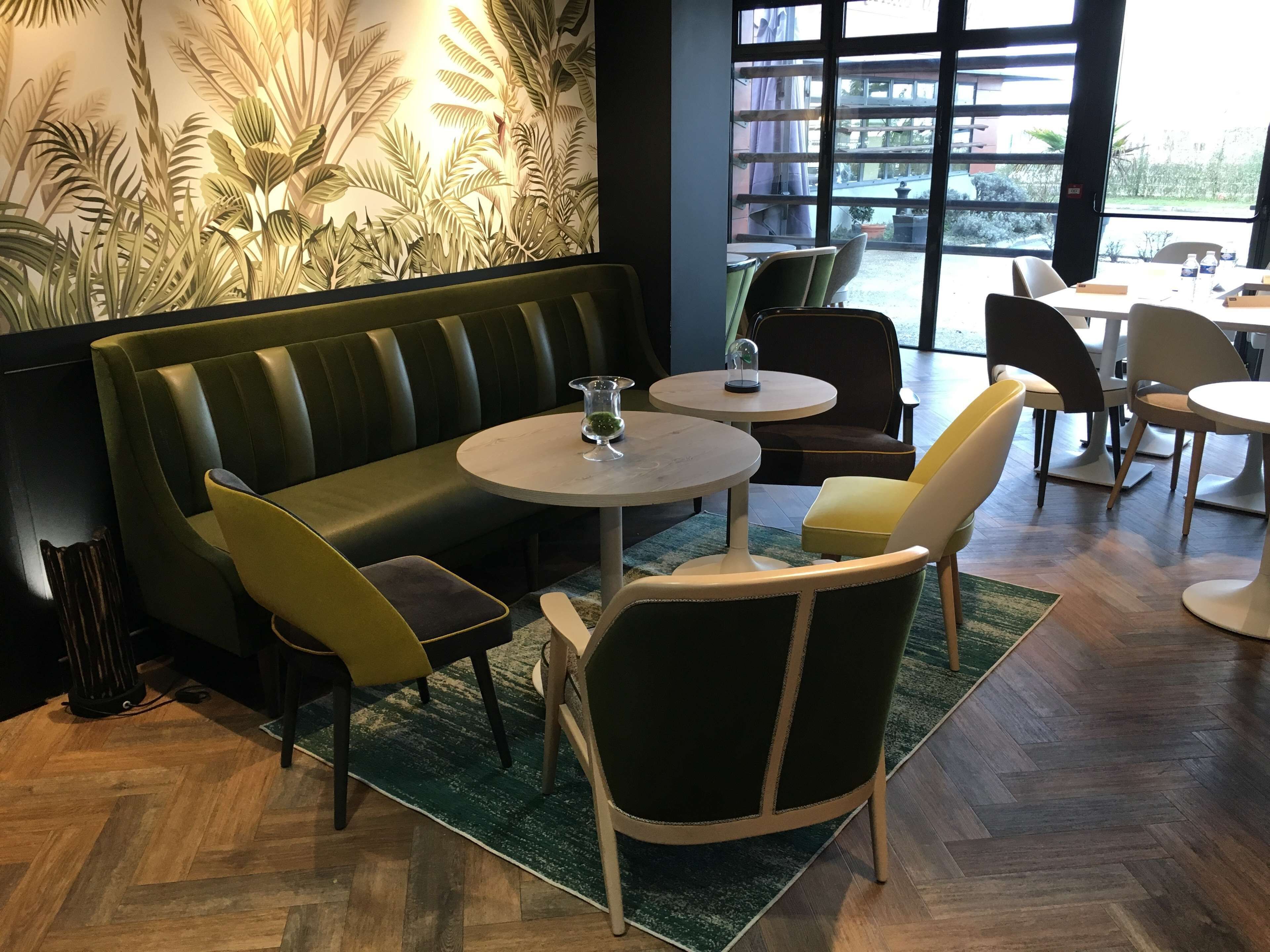 A restaurant with a green booth seating area, round tables, and chairs.
