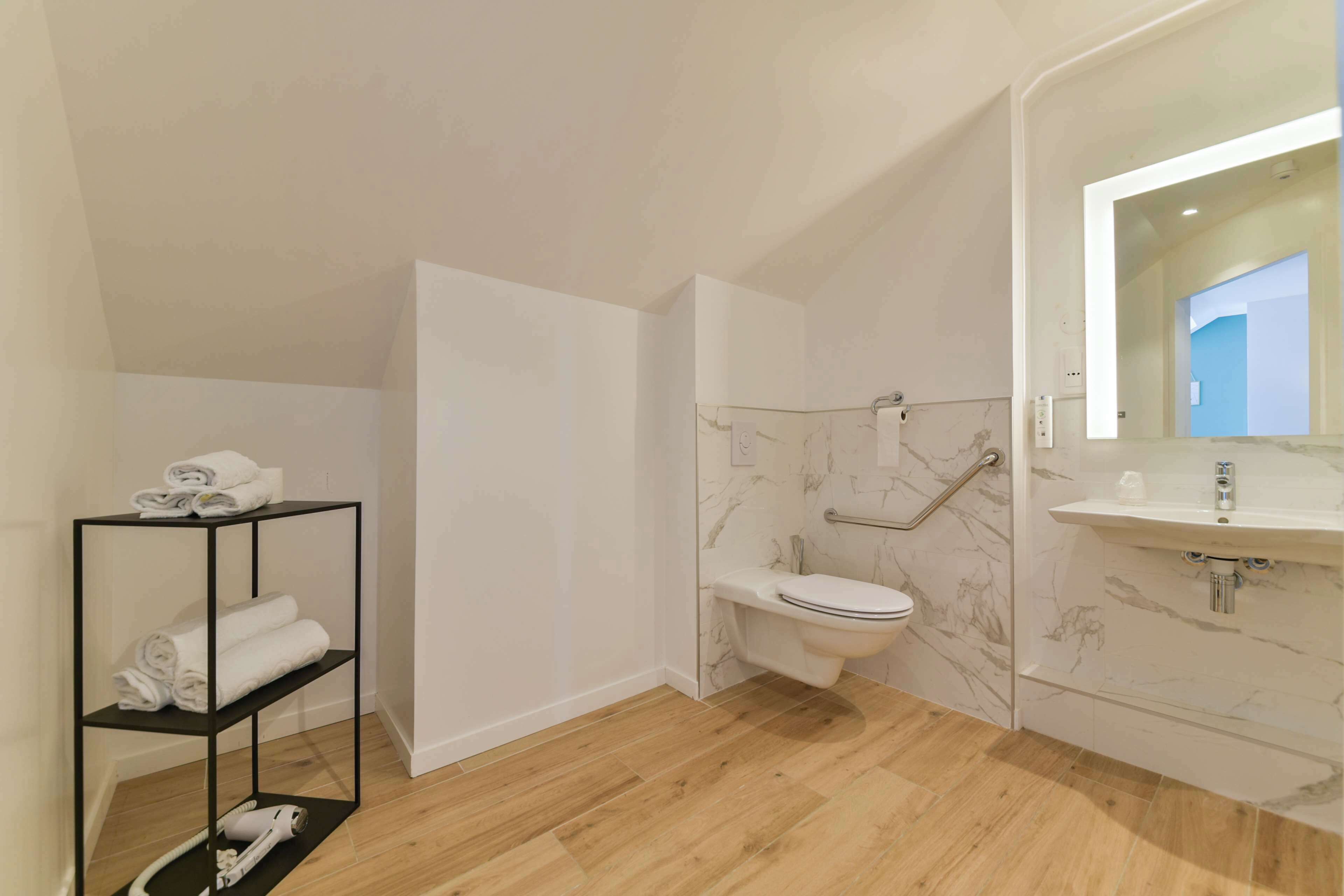 A modern bathroom with a toilet, sink, and a shelf with towels.