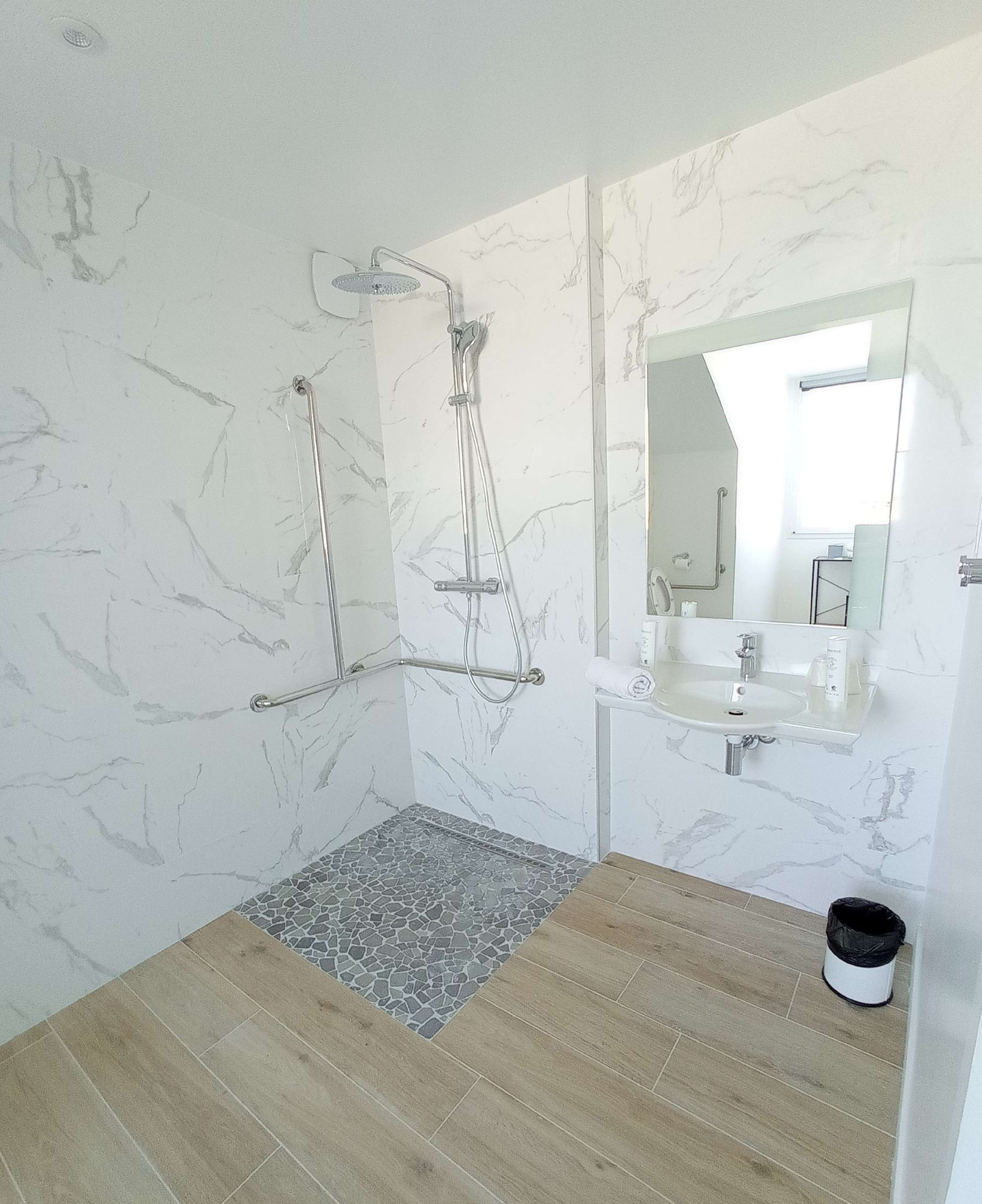 Un baño moderno con ducha, lavamanos y espejo.