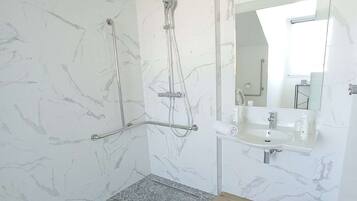 A modern bathroom with a shower, a sink, and a mirror.