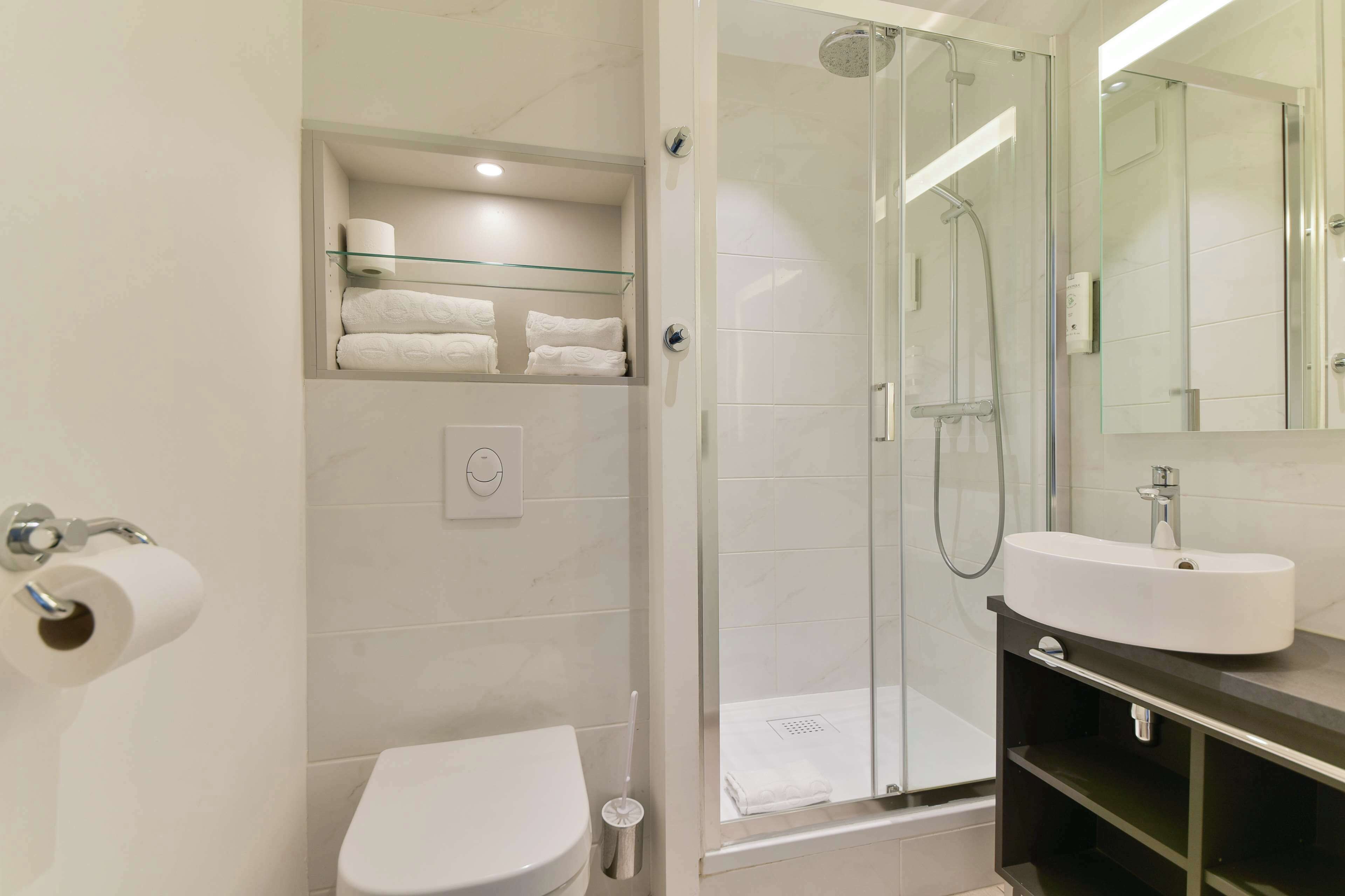 Un bagno moderno con cabina doccia in vetro, lavandino bianco e un water.