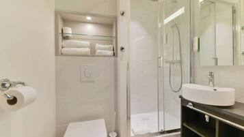 Un bagno moderno con cabina doccia in vetro, lavandino bianco e un water.