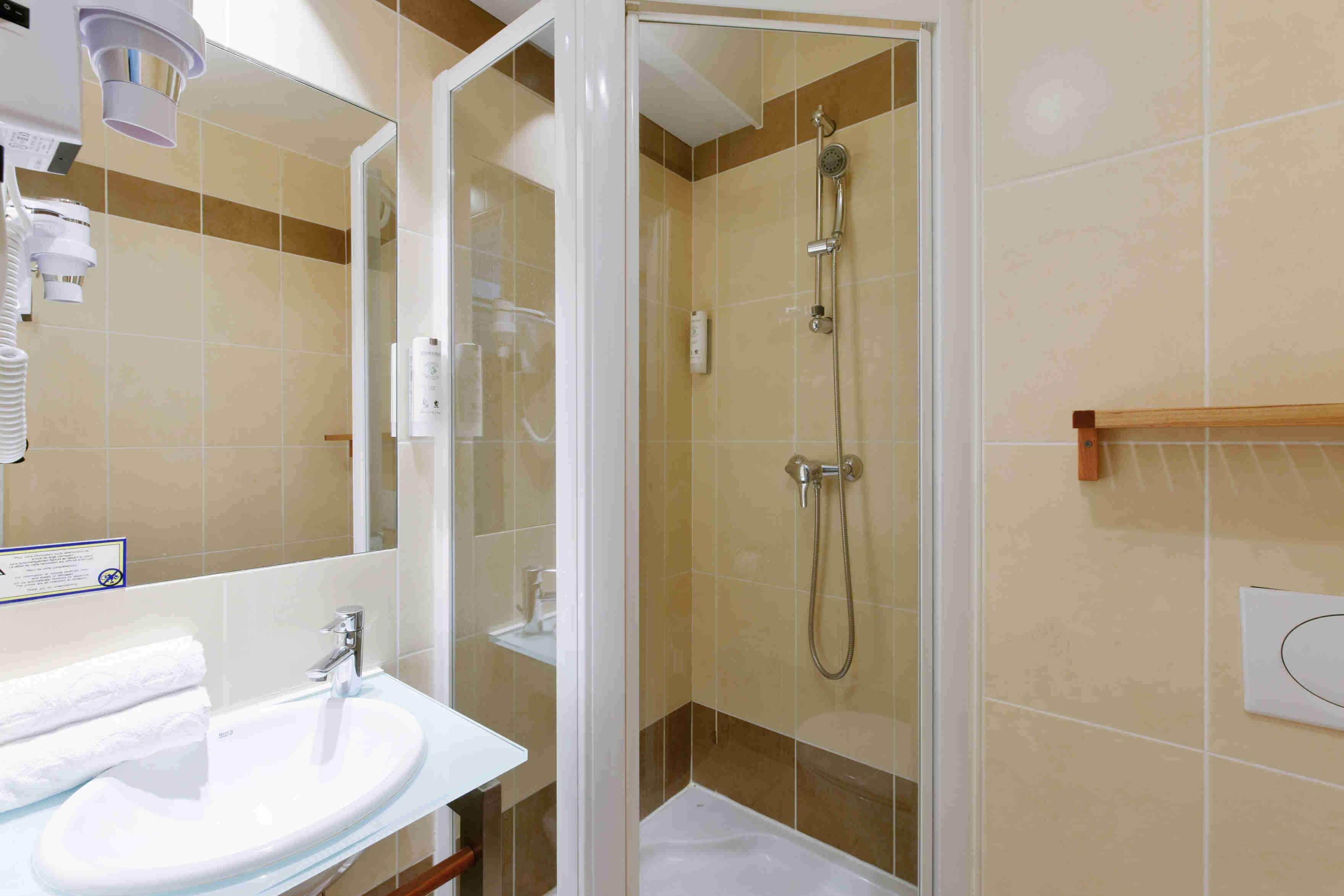 A bathroom with a glass-enclosed shower, a sink, and a mirror.