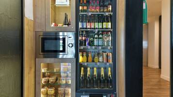 Una macchina distributrice automatica con forno a microonde e un reparto refrigerato contenente diverse bevande e condimenti.