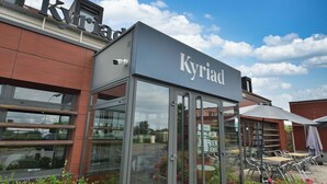 A modern building with a glass entrance and outdoor seating area. - Kyriad Crepy en Valois (Crepy-en-Valois)