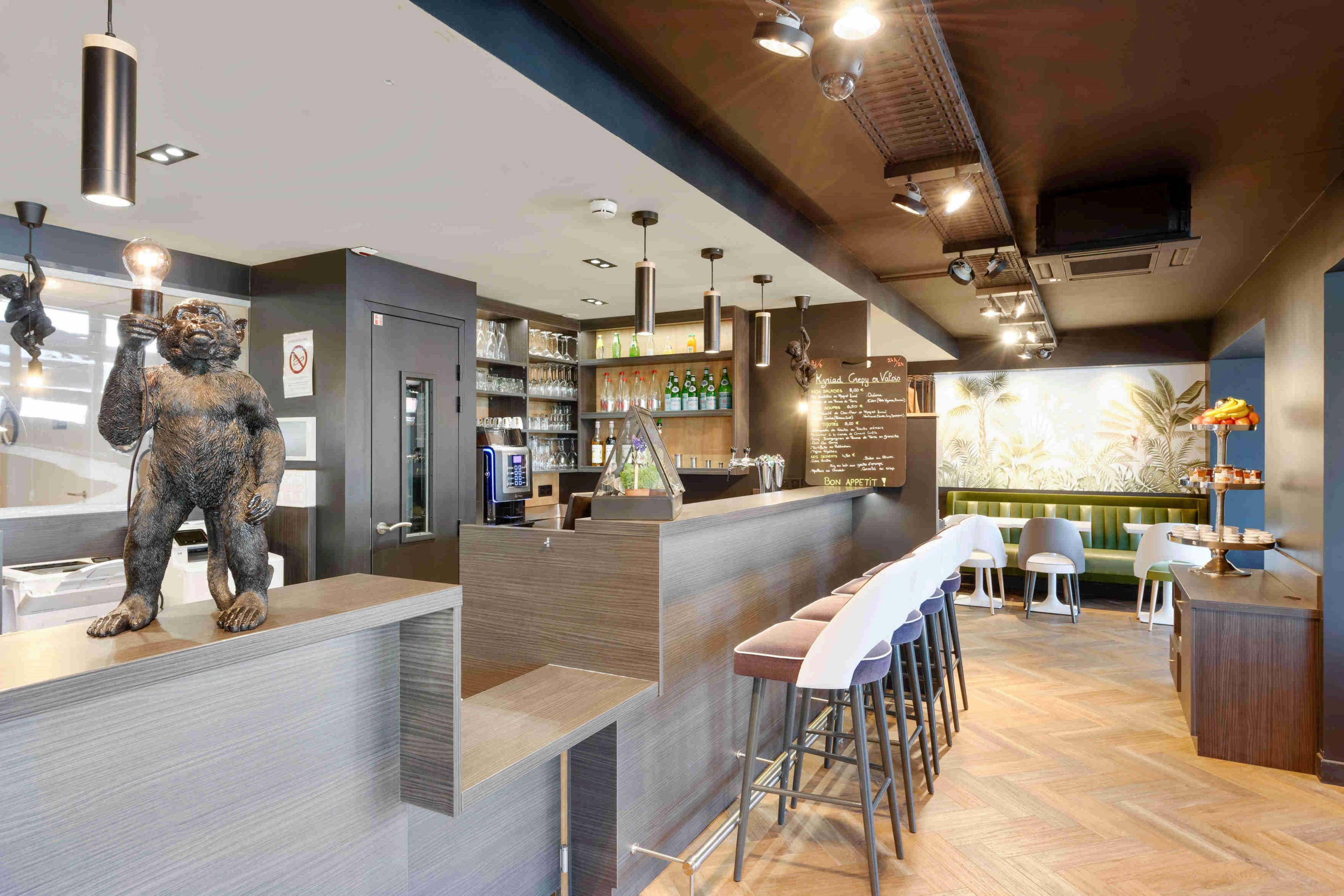 Un espace bar avec des tabourets, un comptoir et un tableau affichant le menu.