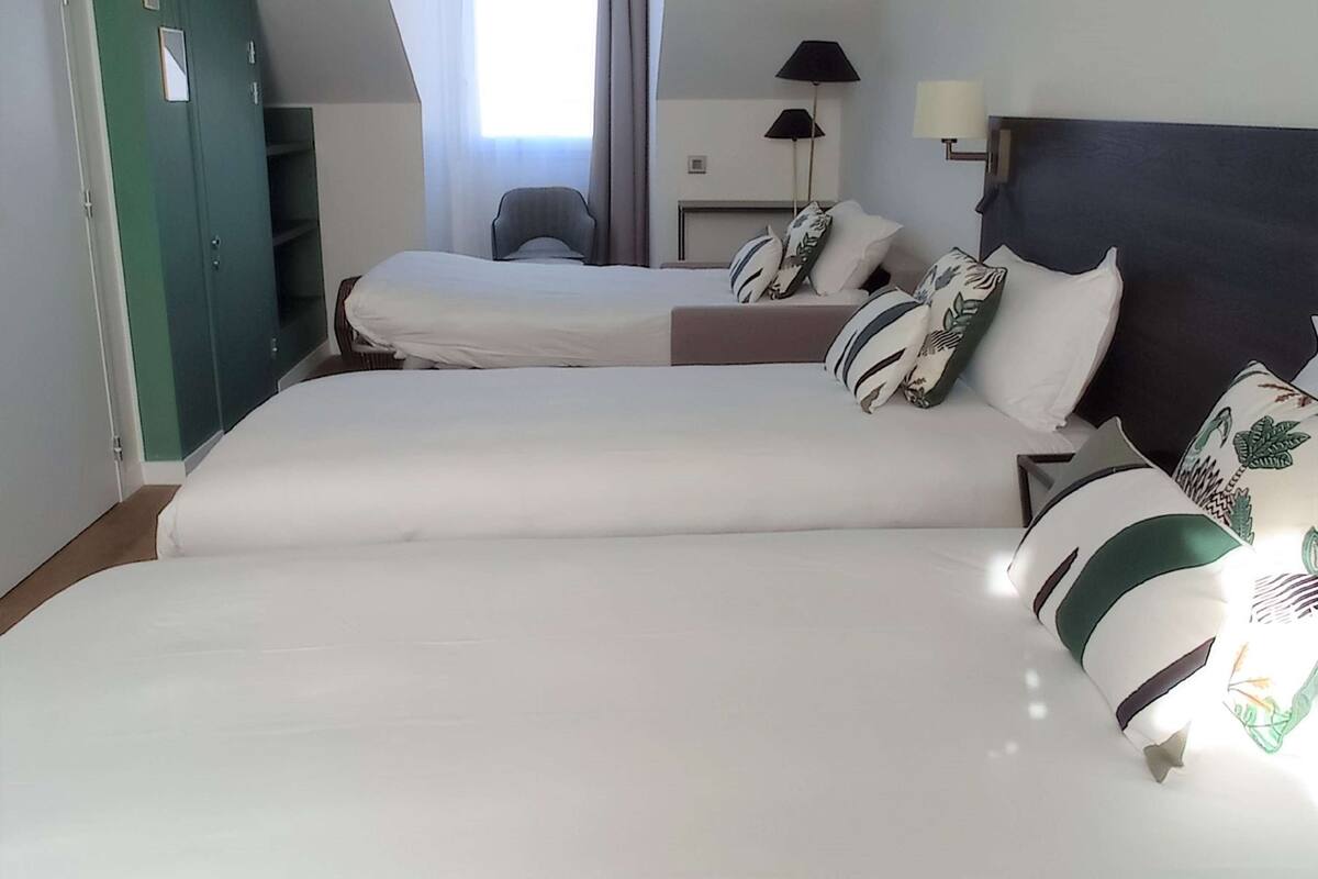 A hotel room with two beds, a desk, a chair, and a window with curtains.