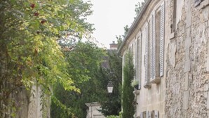 A narrow cobblestone street flanked by historic stone buildings with shutters, leading to a gate. - Kyriad Crepy en Valois (Crepy-en-Valois)