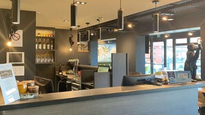 A modern bar area with a counter, hanging lights, and shelves with bottles. - Kyriad Crepy en Valois (Crepy-en-Valois)