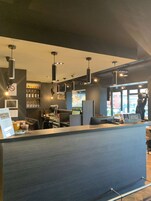 Uma área de bar moderna com balcão, luminárias pendentes e prateleiras com garrafas.