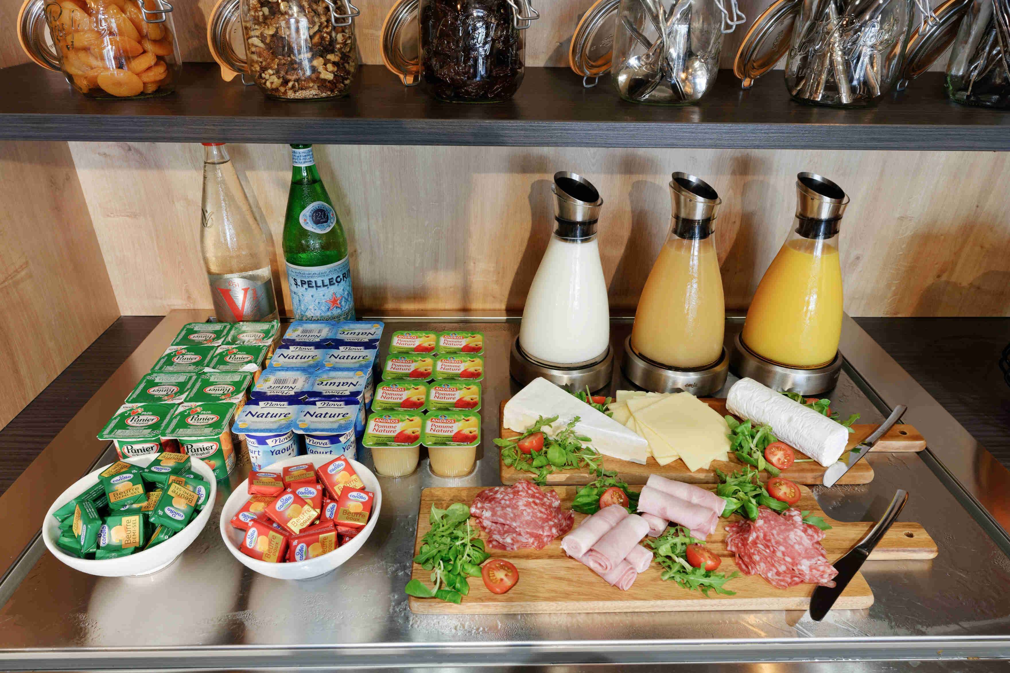 A buffet with various food items, including cheese, meats, and condiments.