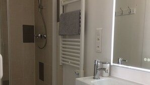 A bathroom with a shower, a sink, and a mirror. - Apartment T2 - LOW SABLONS (Saint-Malo)