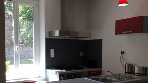 A modern kitchen with a central island, red cabinets, and pendant lighting. - Apartment T2 - LOW SABLONS (Saint-Malo)