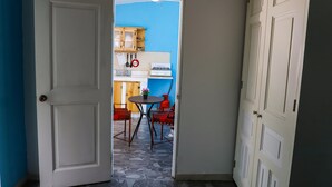 Een gang met een witte deur, een blauwe muur en een keuken die zichtbaar is door een open deur.