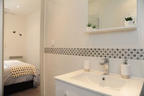 A modern bathroom with a white sink, two toothbrush holders, and a mirror above the sink.