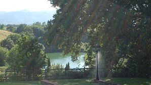 A serene lakeside view with a stone pathway, a lamp post, and a wooden fence. - Residence Il Palazzo_Casa Arezzo (Pergine V.no, AR)